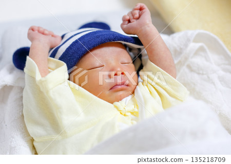 Newborn baby sleeping soundly with arms raised 135218709