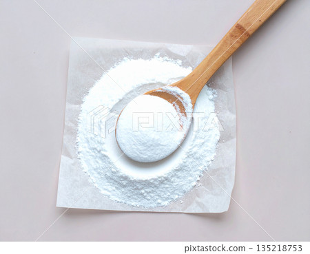 Cleaning concept. Pile of powdered detergent with a wooden spoon on kraft paper on a white background. 135218753