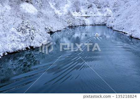 A sightseeing boat sailing through a snow-covered gorge A sightseeing boat sailing through a snow-covered gorge 135218824