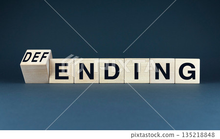 A conceptual image featuring wooden blocks spelling DEFENDING and ENDING. 135218848
