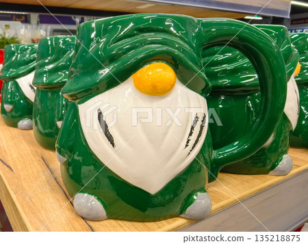 Colorful green mug with whimsical design displayed on wooden shelf Colorful green mug with whimsical design displayed on wooden shelf 135218875
