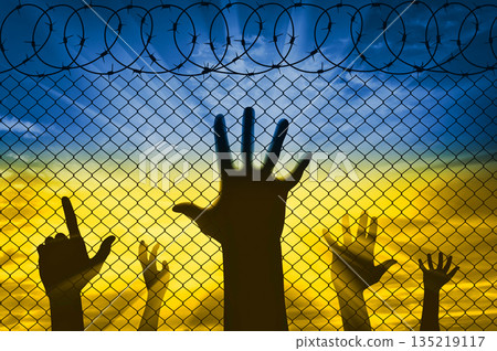 Silhouette of the raised hands of Ukrainian refugees at the border near the barbed wire fence Silhouette of the raised hands of Ukrainian refugees at the border near the barbed wire fence 135219117