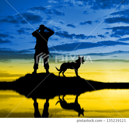 A Ukrainian military man with a dog looks through binoculars 135219121