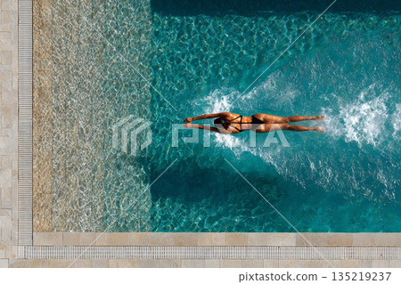Diver performing a graceful springboard dive into a shimmering blue swimming pool Diver performing a graceful springboard dive into a shimmering blue swimming pool 135219237