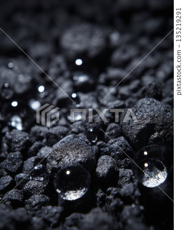 Water droplets resting on dark gravel surface, showcasing natural filtration concept and texture Water droplets resting on dark gravel surface, showcasing natural filtration concept and texture 135219291