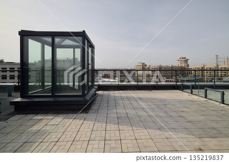 Glass elevator perched above city skyline on neutral terrace 135219837