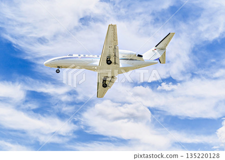 Private business plane flying under blue sky with white cloud 135220128