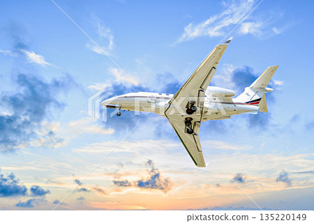 Private business jet flying under the sunset sky	 135220149