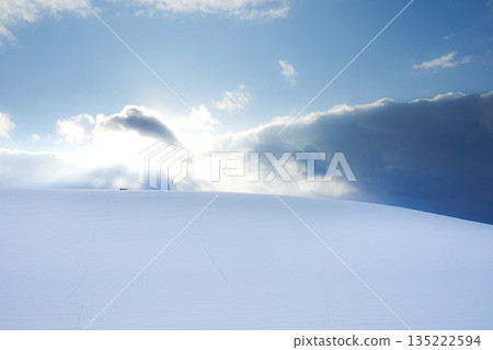 A view of the sun setting over a snowy field seen from a hill in Biei, Hokkaido in mid-winter A view of the sun setting over a snowy field seen from a hill in Biei, Hokkaido in mid-winter 135222594