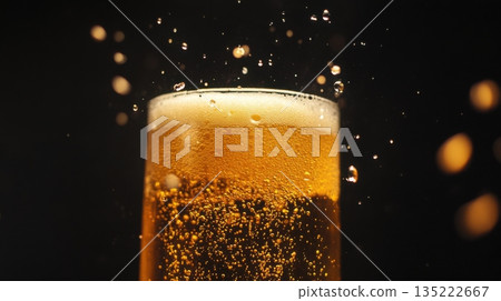 Bubbles rising in a golden beer glass during a festive gathering in a dimly lit brewery 135222667