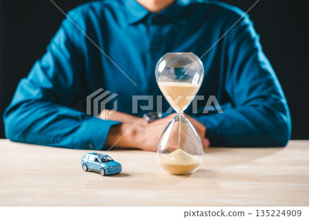 Person evaluates car finance, hourglass shows time running out, emphasizing need for smart money saving and careful buying to manage loan cost insurance and future depreciation 135224909