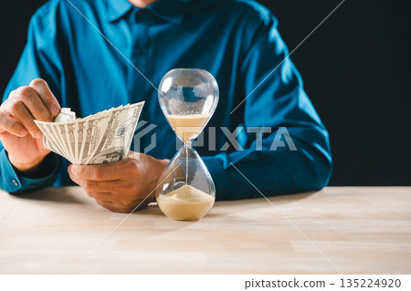 Person counts money banknotes, time sand hourglass flowing on table, illustrating business finance investment concepts, global wealth management, important saving for future Person counts money banknotes, time sand hourglass flowing on table, illustrating business finance investment concepts, global wealth management, important saving for future 135224920