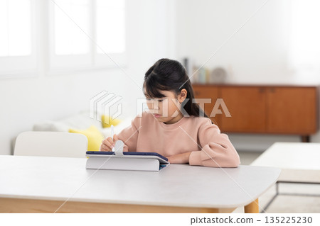 Elementary school girl learning on a tablet Elementary school girl learning on a tablet 135225230