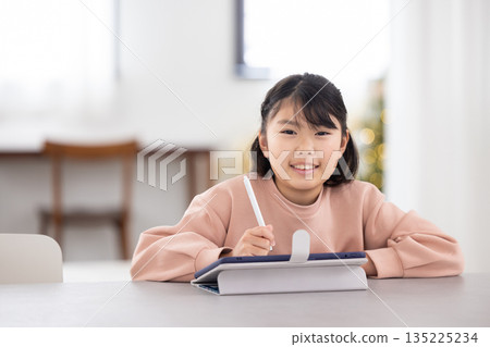 小學生女孩一邊用平板電腦學習一邊微笑 135225234