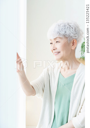 一位老婦人望著窗外。 135225421