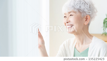 一位老婦人望著窗外。 135225423