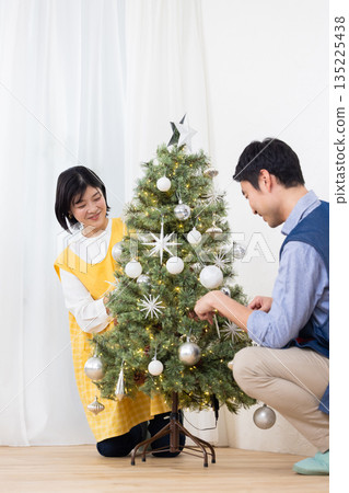 Female and male nursery teachers decorating a Christmas tree 135225438