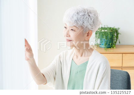 一位老婦人望著窗外。 135225527