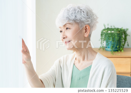 一位老婦人望著窗外。 135225529