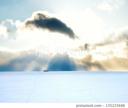 The sun setting over the snowy fields of Biei, Hokkaido in winter, and rays of light from the clouds 135225686
