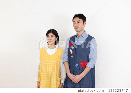 Smiling male and female nursery teachers wearing aprons 135225747