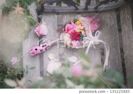 Pink shovel and roses on a bench 135225885