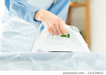 Hands of a woman ironing a dress shirt Hands of a woman ironing a dress shirt 135226031