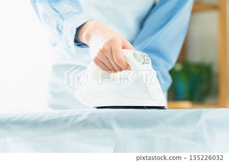 Hands of a woman ironing a dress shirt Hands of a woman ironing a dress shirt 135226032