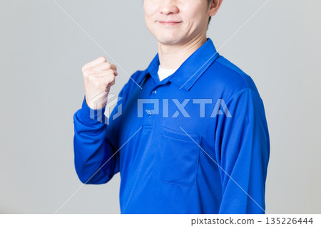 一名身穿藍色物流運輸業工作服的中年男子揮拳慶祝 135226444