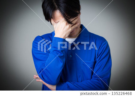 A middle-aged man wearing blue work clothes in the logistics and transportation industry who is depressed A middle-aged man wearing blue work clothes in the logistics and transportation industry who is depressed 135226468