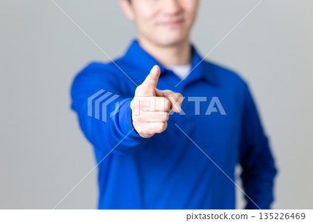 A middle-aged man wearing blue work clothes in the logistics and transportation industry pointing A middle-aged man wearing blue work clothes in the logistics and transportation industry pointing 135226469