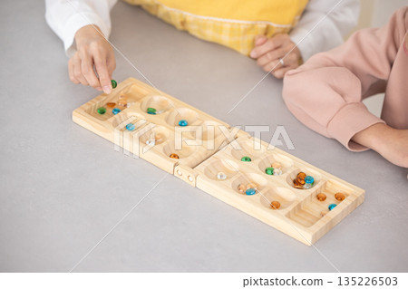 Close-up of parent and child playing Mancala Close-up of parent and child playing Mancala 135226503