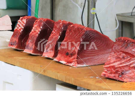 Raw tuna being cut into pieces Raw tuna being cut into pieces 135226656