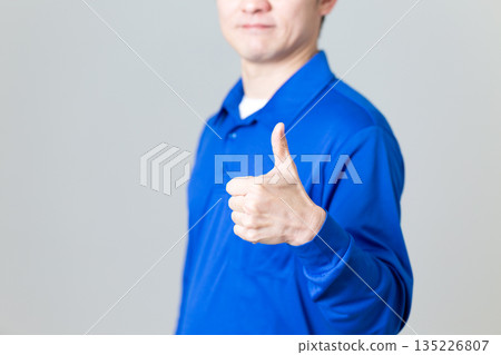 一名身穿藍色物流運輸業工作服的中年男子揮拳慶祝 135226807