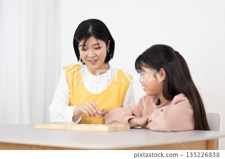 A female after-school teacher teaching female students A female after-school teacher teaching female students 135226838