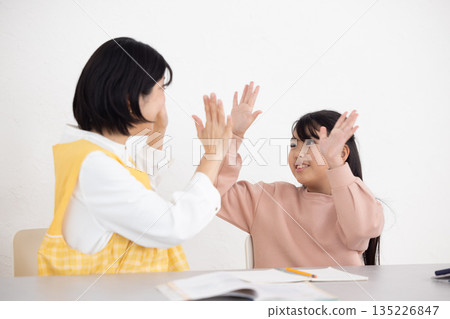 一名女學生和一名穿著圍裙的課後輔導女老師互相擊掌 135226847