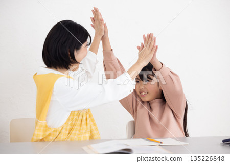 一名女學生和一名穿著圍裙的課後輔導女老師互相擊掌 一名女學生和一名穿著圍裙的課後輔導女老師互相擊掌 135226848
