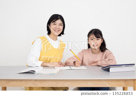 A female after-school teacher teaching female students A female after-school teacher teaching female students 135226853