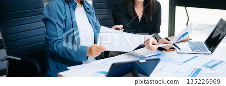 Asian senior and middle aged businesswomen reviewing documents and reports in office. Professional teamwork, mentorship, business collaboration 135226969