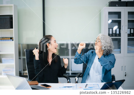 Asian senior and middle aged businesswomen reviewing documents and reports in office. Professional teamwork, mentorship, business collaboration Asian senior and middle aged businesswomen reviewing documents and reports in office. Professional teamwork, mentorship, business collaboration 135226982