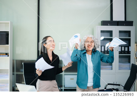 Happy Asian businesswomen celebrating teamwork success in office. Corporate achievement, business victory, motivation Happy Asian businesswomen celebrating teamwork success in office. Corporate achievement, business victory, motivation 135226993