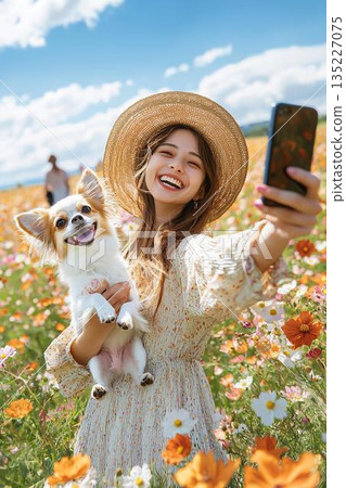 Smiling woman taking a selfie with her dog in a flower field Smiling woman taking a selfie with her dog in a flower field 135227075