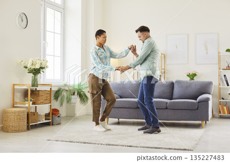 Happy couple dancing together in cozy living room at home, enjoying leisure time 135227483