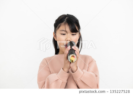 A girl eating a whole ehomaki 135227528
