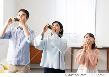 A family of three eating ehomaki whole in a bright living room A family of three eating ehomaki whole in a bright living room 135227583