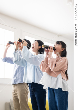 A family of three eating ehomaki whole in a bright living room A family of three eating ehomaki whole in a bright living room 135227587