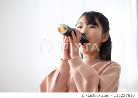 A girl eating a whole ehomaki A girl eating a whole ehomaki 135227636