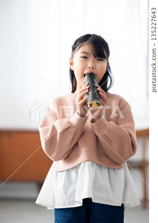 A girl eating a whole ehomaki A girl eating a whole ehomaki 135227643