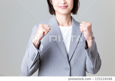 A middle-aged businesswoman in a gray suit making a fist pump A middle-aged businesswoman in a gray suit making a fist pump 135228266
