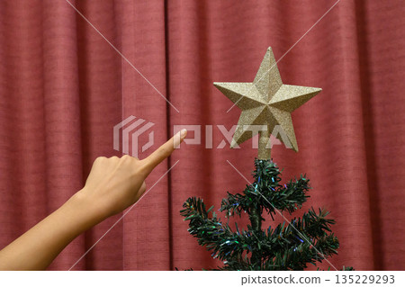 一隻人手指向聖誕樹上的星星 135229293